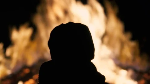 Silhouette of a boy staring at a bonfire burning in the night Stock Footage 72480253