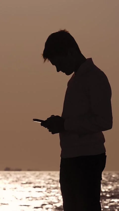 Silhouette of a Boy Using Smartphone at Sunset Stock Footage 287136282