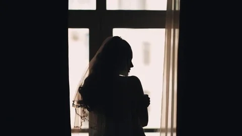 Silhouette of bride girl waiting for fiance in front of window Stock Footage