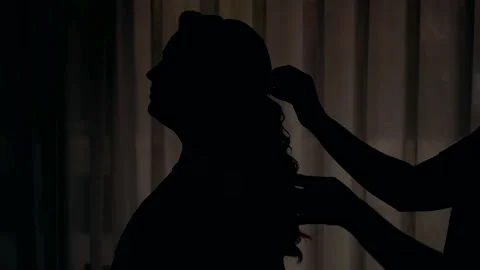 Silhouette of a bride whose bridesmaid is doing her hair. Video stock 224297489