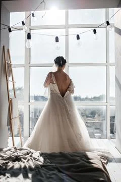 The silhouette of the bride at the window putting on her dress Stock Photos