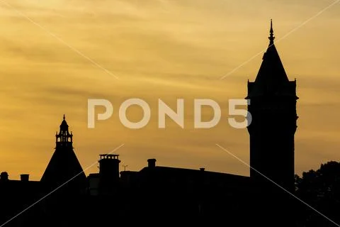 Silhouette of building towers with colourful golden sunset sky and clouds Stock Photos