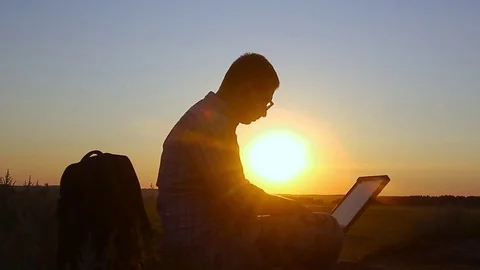 Silhouette of business man with laptop working on the field at sunset time. Conc Stock Footage