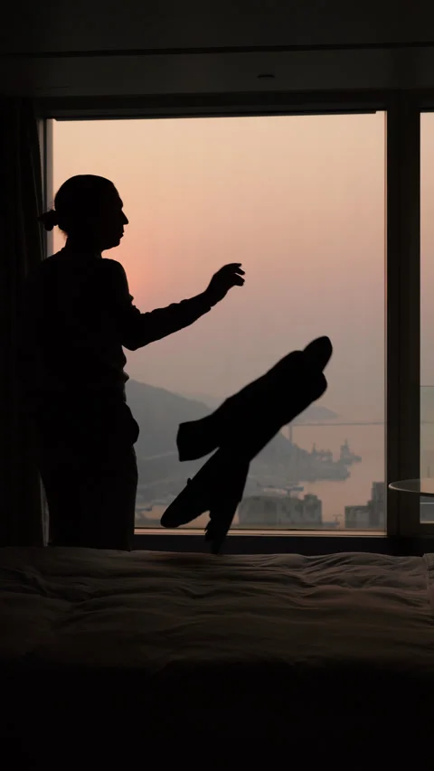 Silhouette of a businessman throwing jacket on bed and stay akimbo at sunset Stock Footage 341004633