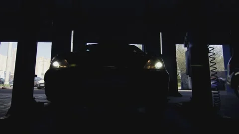 Silhouette of a car leaving after service with headlights light up in the dark Stock Footage 281582553