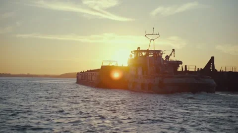 Silhouette of a cargo barge on a sunset background. Transportation of goods by Stock Footage 135594349