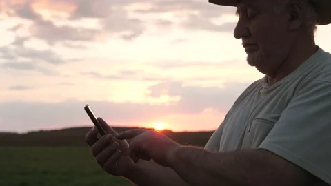 Silhouette Of A Caucasian Man In A Field Using A Smartphone Against The Sun Rays Stock Footage 138738600