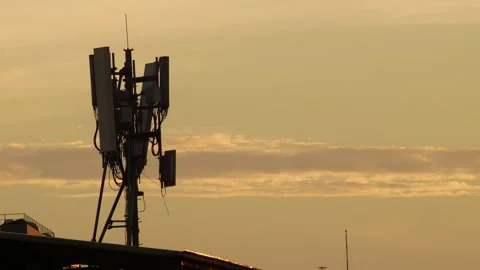 Silhouette of Cell Tower Antenna Array Against Dramatic Orange Sunset 스톡 동영상 345660944
