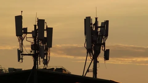 Silhouette of Cell Tower Antenna Array Against Dramatic Orange Sunset Stock Footage 346298932