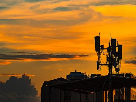 Silhouette of Cell Tower Antenna Array Against Dramatic Orange Sunset Stock Photos