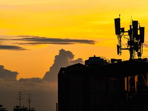Silhouette of Cell Tower Antenna Array Against Dramatic Orange Sunset Stock Photos