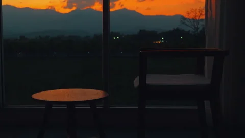 Silhouette of chair and table by window overlooking stunning sunset Video stock 282301871