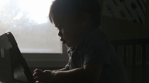 Silhouette of child looking at electronic device, video Stock Footage 79720362