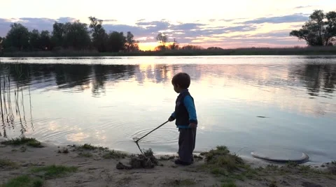 Silhouette of child playing at the riverside Stock Footage 64907589
