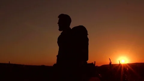 Silhouette of climber with backpack at sunset. Stock Footage