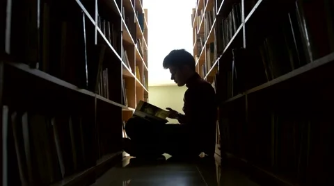 Silhouette college student sitting on floor in library Stock Footage