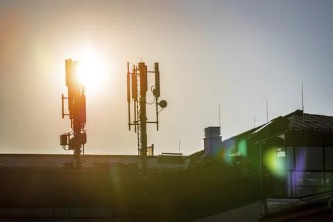 Silhouette of communication or cell tower on the rooftop of a building, evening Stock Photos