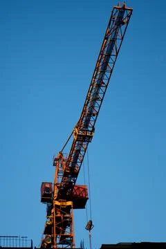 Silhouette of construction crane and unfinished residential building Stock Photos