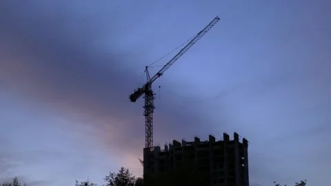 Silhouette of a construction crane at a construction site with an unfinished Stock Footage 201099021