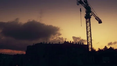 Silhouette of a construction crane at dusk over roof with lot of water heaters. 스톡 동영상 84199208