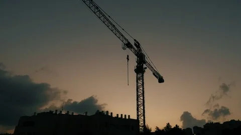 Silhouette of a construction crane at dusk over roof with lot of water heaters. 스톡 동영상 84789470