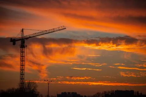 Silhouette of construction crane in front of sunset Stock Photos