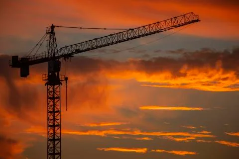 Silhouette of construction crane in front of sunset Stock Photos