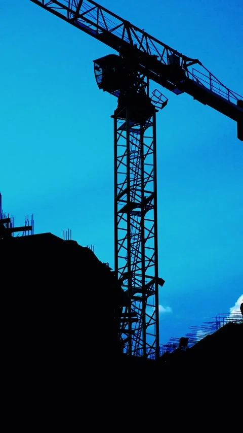 The silhouette of a construction crane stands out boldly against a vibrant blue Stock Footage 290191769