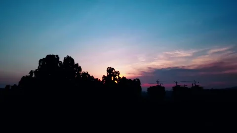 Silhouette of construction site and trees against a vibrant sunset sky at dusk Stock Footage 341946921
