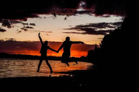 Silhouette of couple hold each other hand on the beach at sunset time Stockfoto's