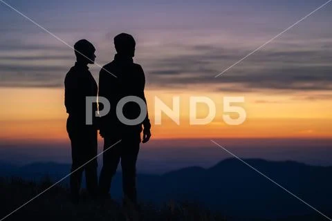 The silhouette of the couple on the mountain with a sunrise background Stock Photos