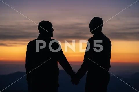 The silhouette of the couple on the mountain with a sunrise background Stock Photos