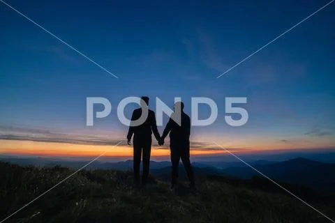 The silhouette of the couple on the mountain sunset background Stock Photos