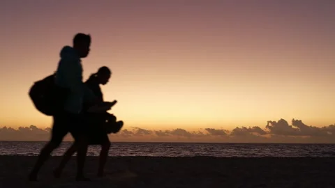 Silhouette of a couple walking at dawn on a sandy beach in Yucatan Mexico Stock Footage 346247555