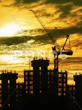 Silhouette of crane and building construction and sun set sky with copy space Stock Photos