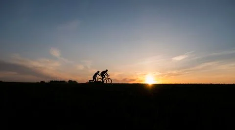 Silhouette of cyclist and running man without bike in motion on the background Stock Photos