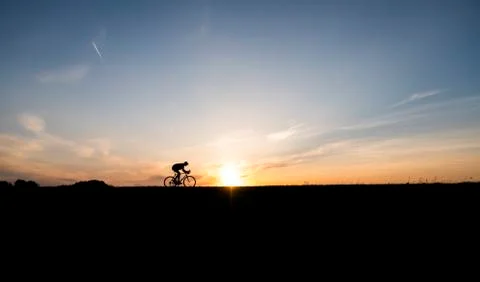 Silhouette of cyclist in motion on the background of beautiful sunset. Male ride Stock Photos
