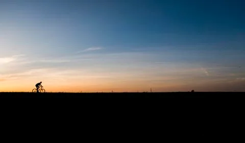 Silhouette of cyclist in motion on the background of beautiful sunset. Male ride Stock Photos