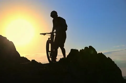 Silhouette Of A Cyclist Standing on Clif Against The Sun Stock Photos