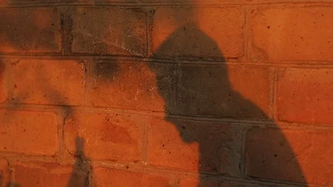 Silhouette of depressed man drinking alone on wall. Unhappy guy crying Stock Footage 99376110