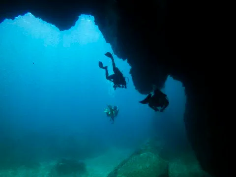 Silhouette divers in a cave Stock Photos