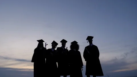 Silhouette of Diverse International Students Celebrating Graduation Tossing Caps Stock Footage