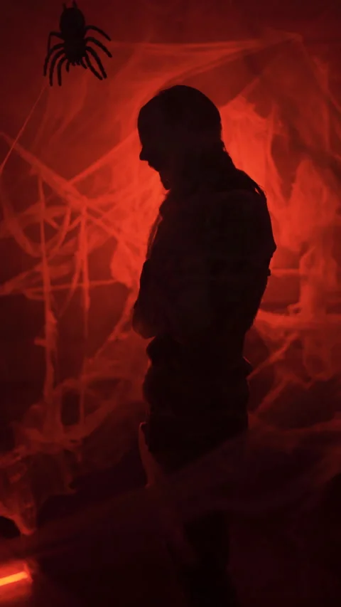 Silhouette of Dramatic zombie man trapped in spiderwebs with big spider on red Stock Footage 318902391