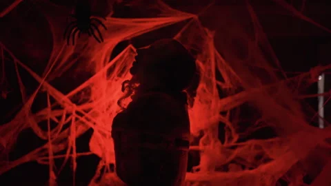 Silhouette Dramatic zombie man trapped in spiderwebs with big spider on red Stock Footage 319056155