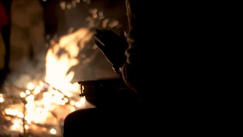 Silhouette of drummer playing with hands on drum by campfire Stock Footage 107542260