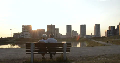 Silhouette of an elderly couple sitting on a bench against the backdrop of a Stock Footage 135579451