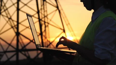 Silhouette electrical engineer, work computer tablet sunset, electric tower Foto stock