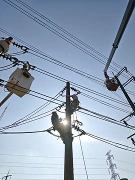 Silhouette of electrical lineman team workers climbing concrete pole. Stock Photos