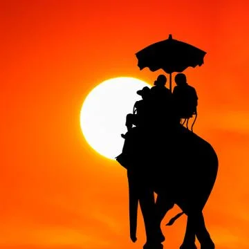 Silhouette elephant with tourist at sunset Stock Photos