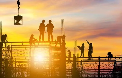 Silhouette of Engineer and worker on building site sunset in evening time. Fotos Stock
